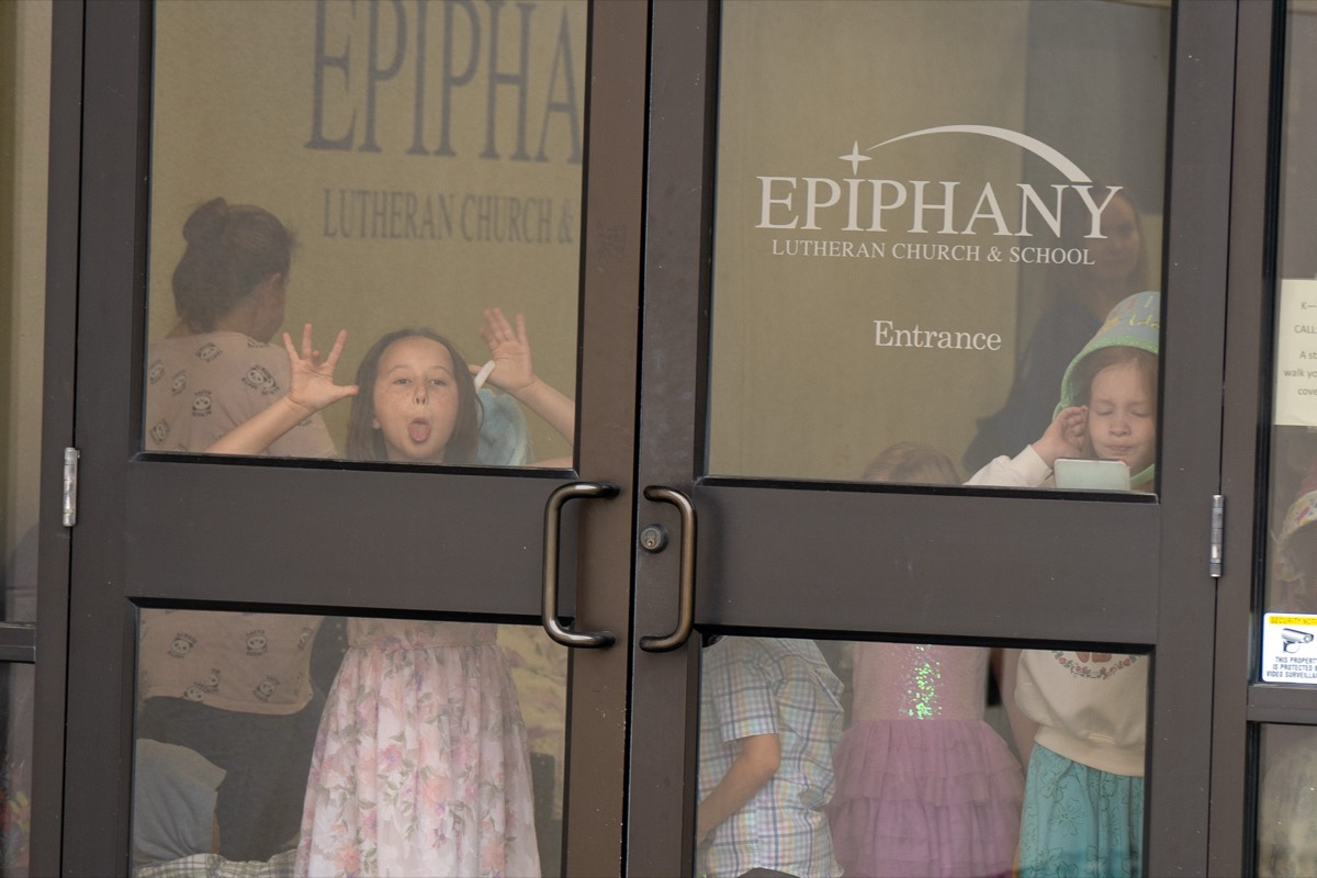 Kids making silly faces through the glass entrance doors of Epiphany Lutheran Church and School