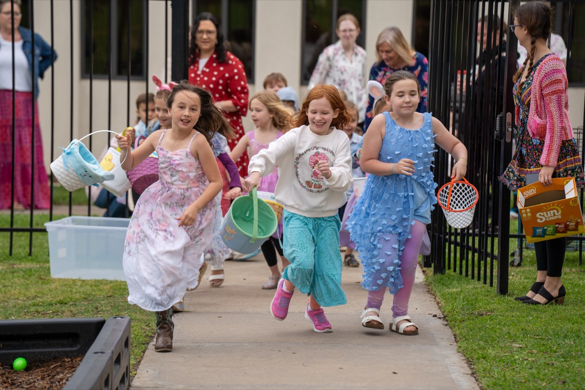 Children racing down the sidewalk with baskets at the Epiphany Easter egg hunt